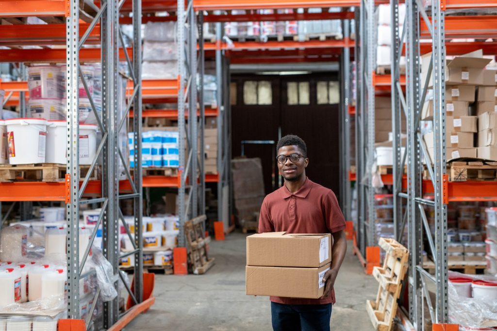 Young storeroom worker carrying order to customer